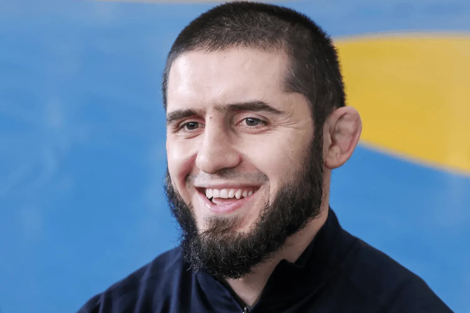 Islam Makhachev smiles while being asked questions by a reporter