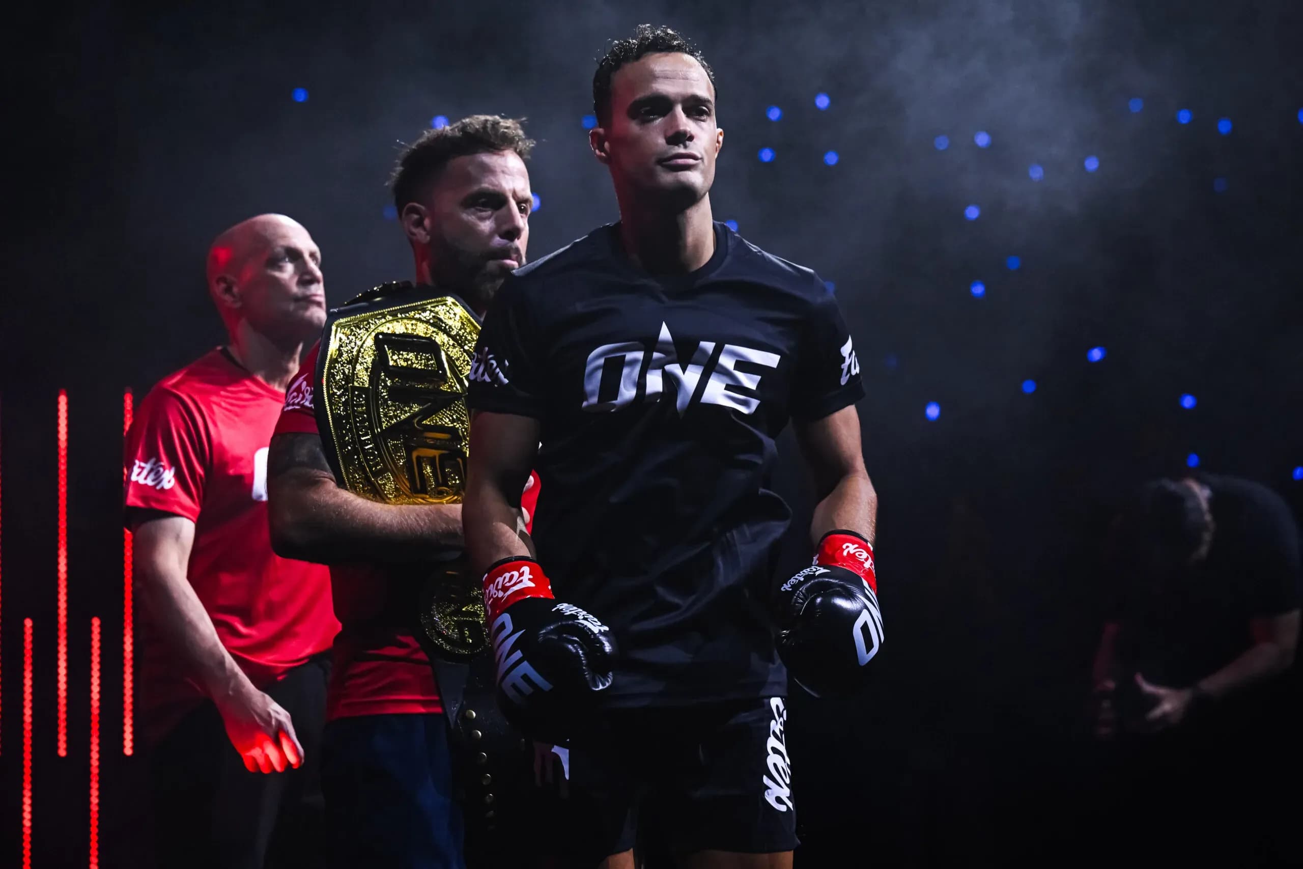 Jonathan Di Bell walks to the ring, with his cornermen carrying his ONE Championship belt