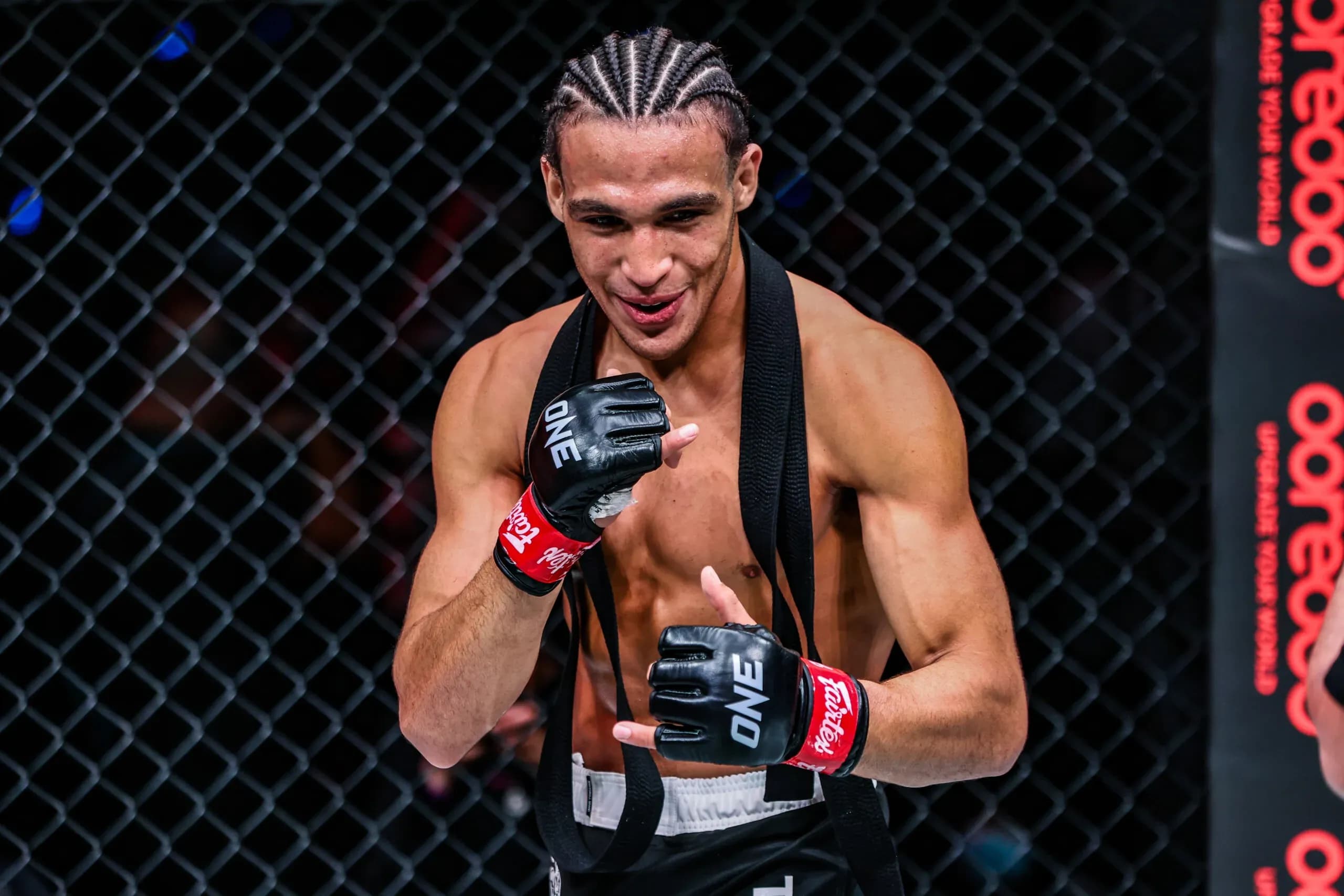 Kade Ruotolo poses in the cage with his MMA gloves and black belt