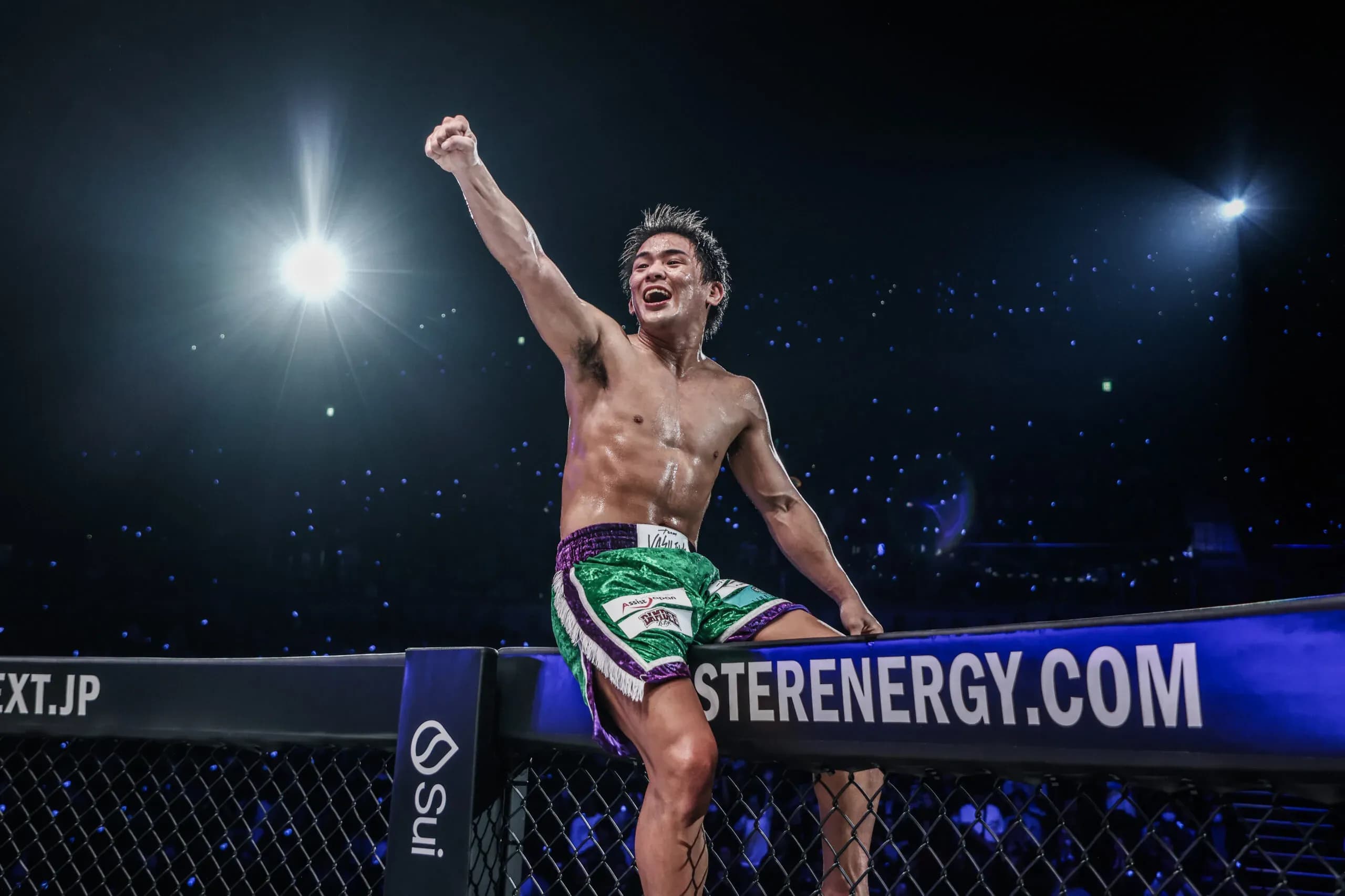 Japanese kickboxer Yuki Yoza pumps his fist and sits on top of the cage