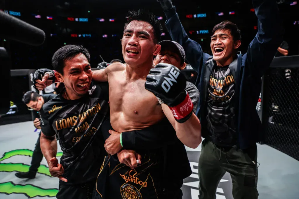 Joshua Pacio celebrates a win with his team inside the cage