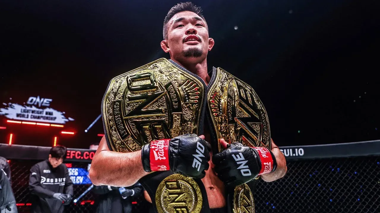 Christian Lee holding two belts